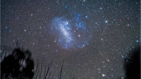 南半球夜空中的麦哲伦云，一团弥散的蓝白色星光悬在密布的星场里